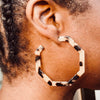 Right ear of a person wearing an ivory and brown coloured hexagon shaped hoop pierced earring 