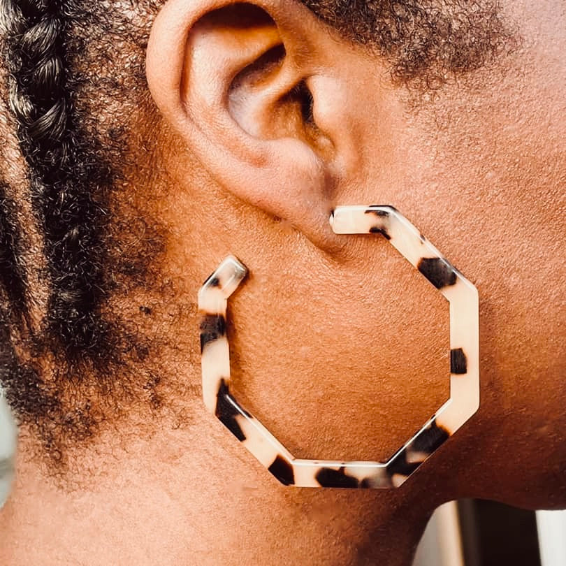 Right ear of a person wearing an ivory and brown coloured hexagon shaped hoop pierced earring 