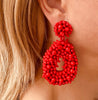 Right ear of a person wearing a large, red, beaded teardrop shape statement earring