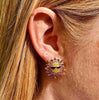 Right ear of a person wearing a sun shaped stud earring with sunglasses and multicolour crystal design