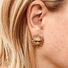 Right ear of a person wearing a sun shaped stud earring with sunglasses and bronze and yellow crystal design