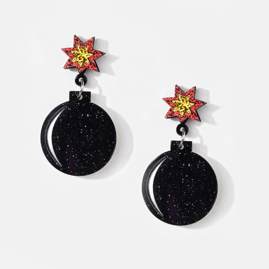 Pair of acrylic stud and pendant earrings in black, yellow and red in the shape of a firecracker, with light glitter design