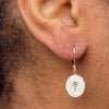 Right ear of a person wearing a small rose gold earring with small pendant with palm tree and zircon design